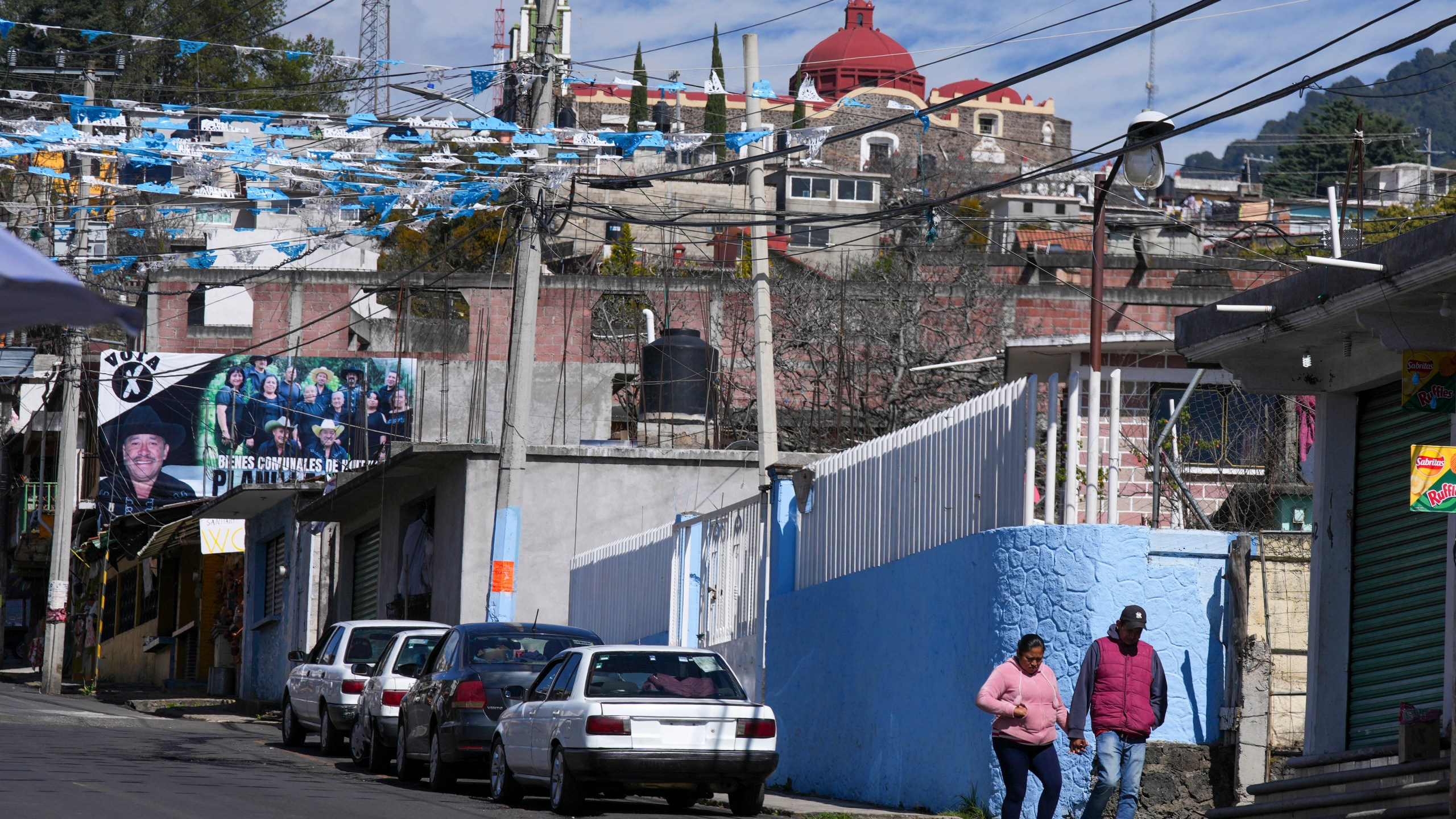 Residents walk near a street where five people were killed the night before, in Huitzilac, Mexico, Tuesday, Jan. 14, 2025. (AP Photo/Fernando Llano)