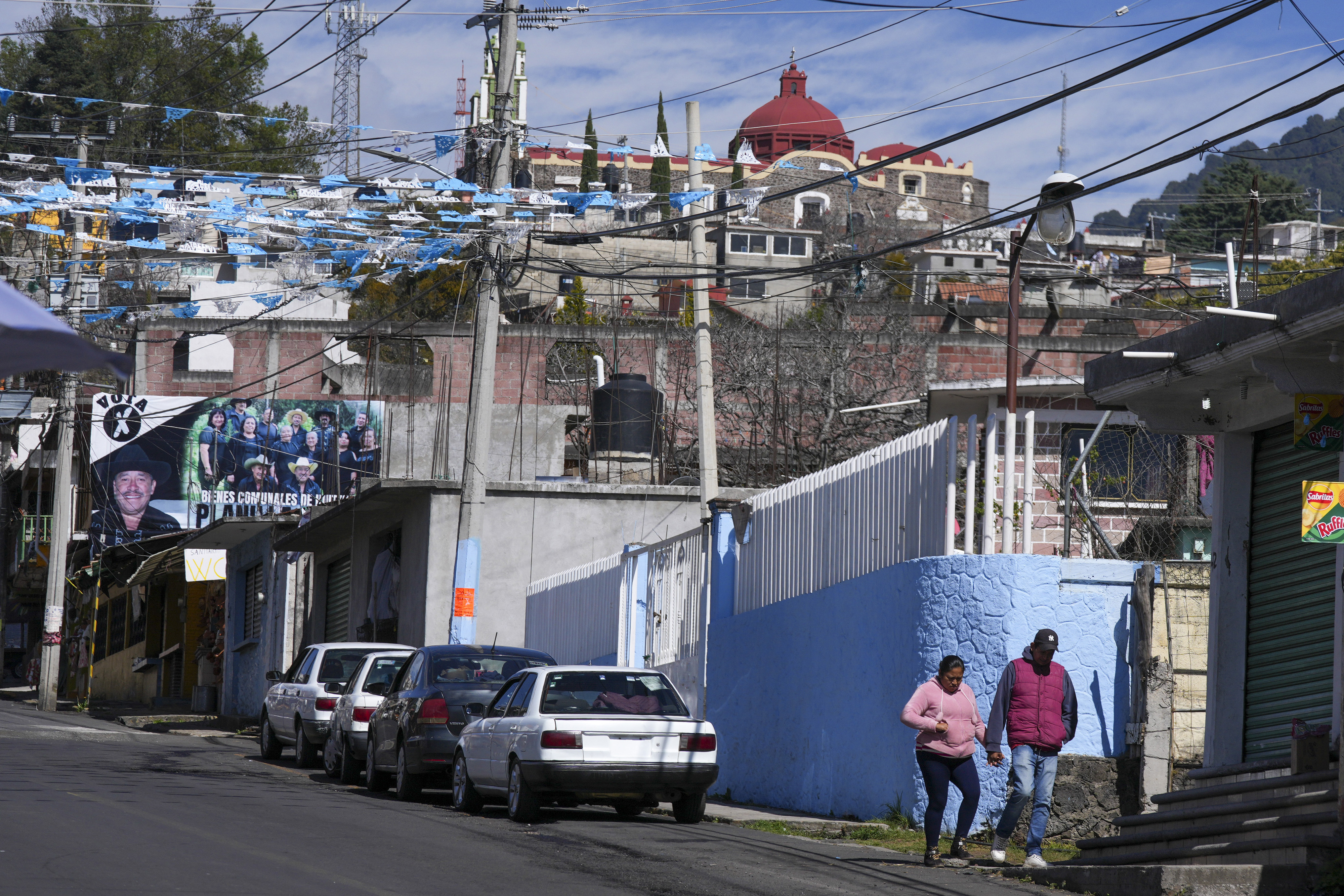 Residents walk near a street where five people were killed the night before, in Huitzilac, Mexico, Tuesday, Jan. 14, 2025. (AP Photo/Fernando Llano)