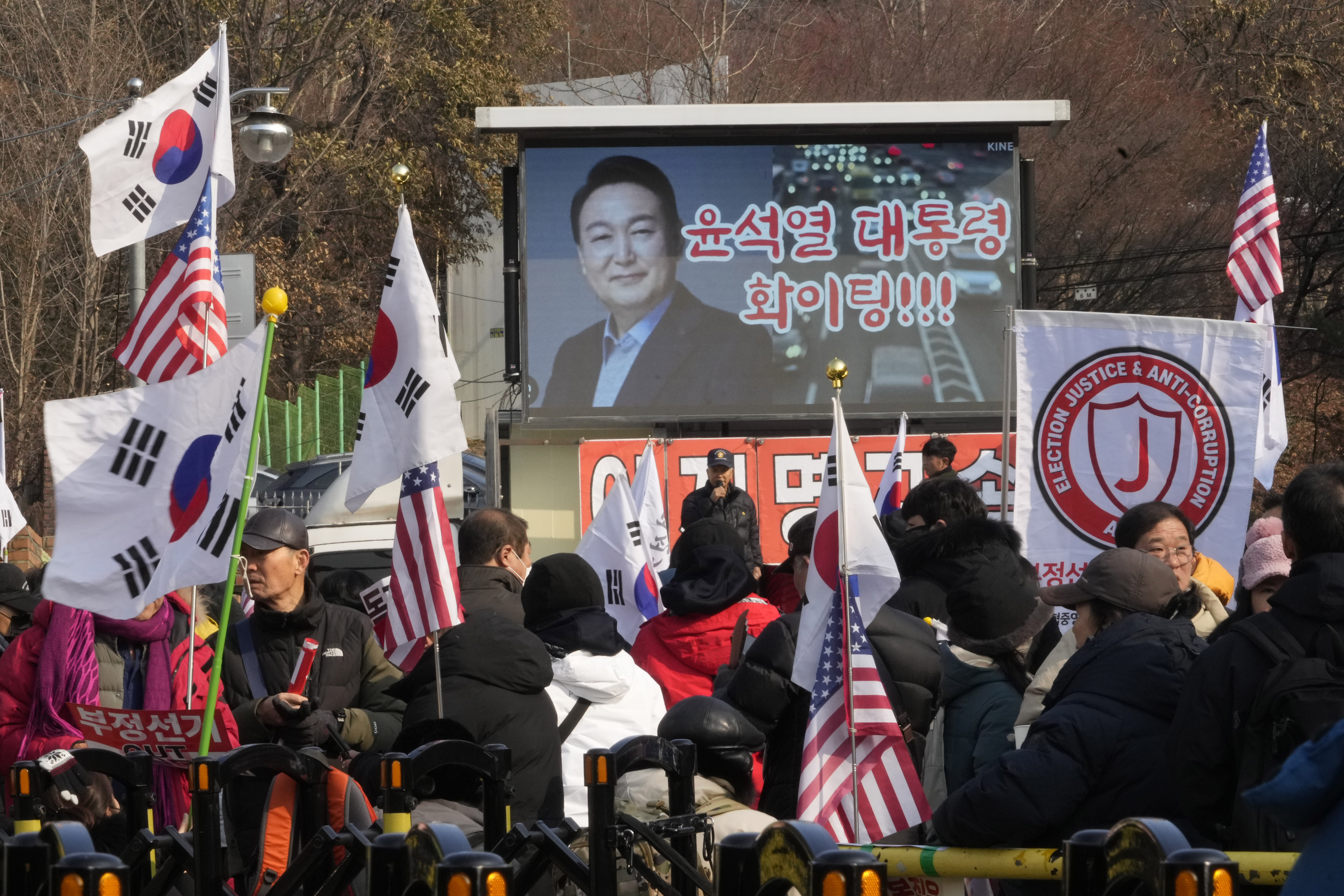 A TV screen shows a file image of South Korean President Yoon Suk Yeol as supporters of impeached Yoon stage a rally to oppose his impeachment near the presidential residence in Seoul, South Korea, Sunday, Jan. 12, 2025. The letters read "Fighting President Yoon Suk Yeol." (AP Photo/Ahn Young-joon)