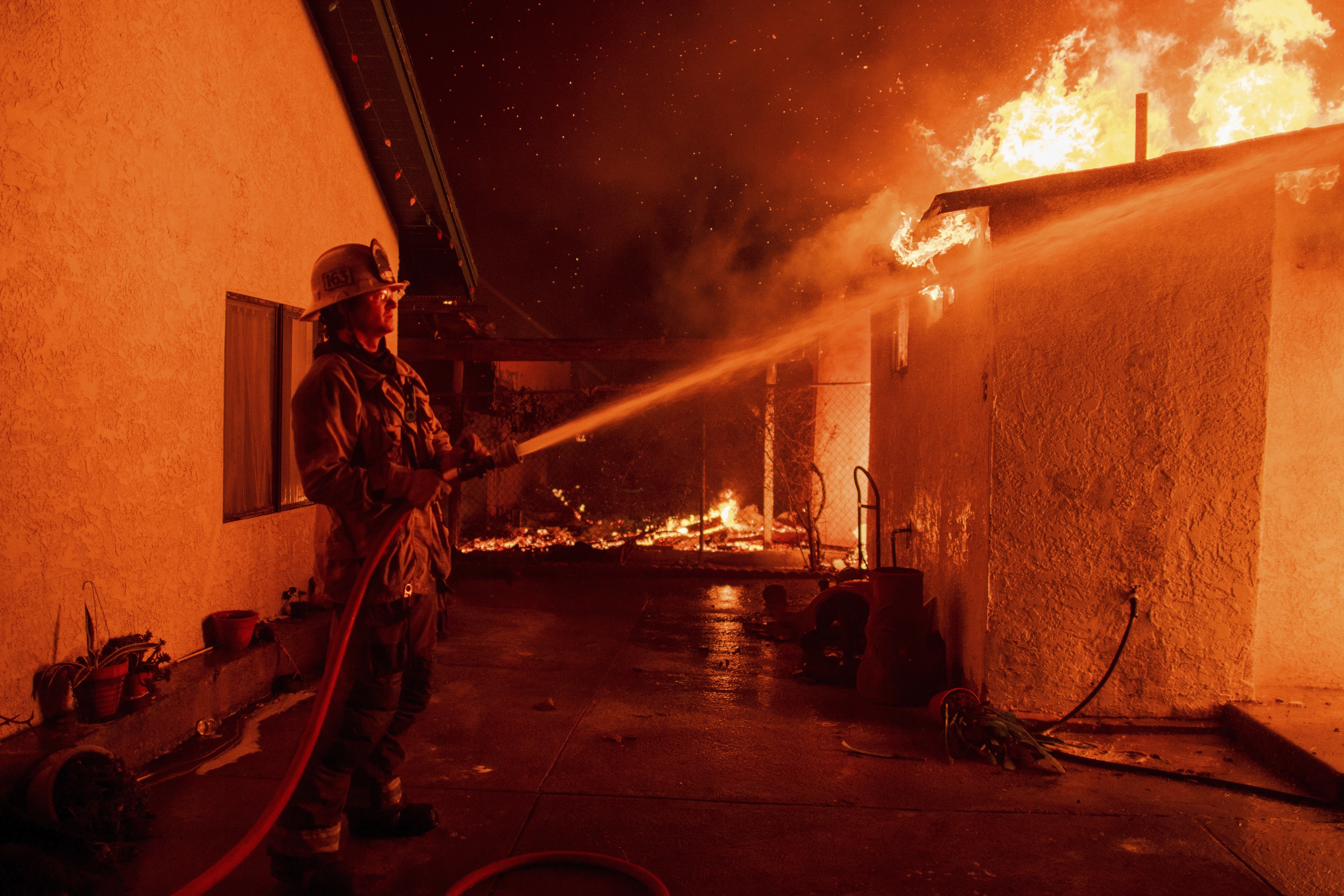 FILE - A firefighter sprays water on a garage burning in the Eaton Fire in Altadena, Calif., Jan. 8, 2025. (AP Photo/Nic Coury, File)