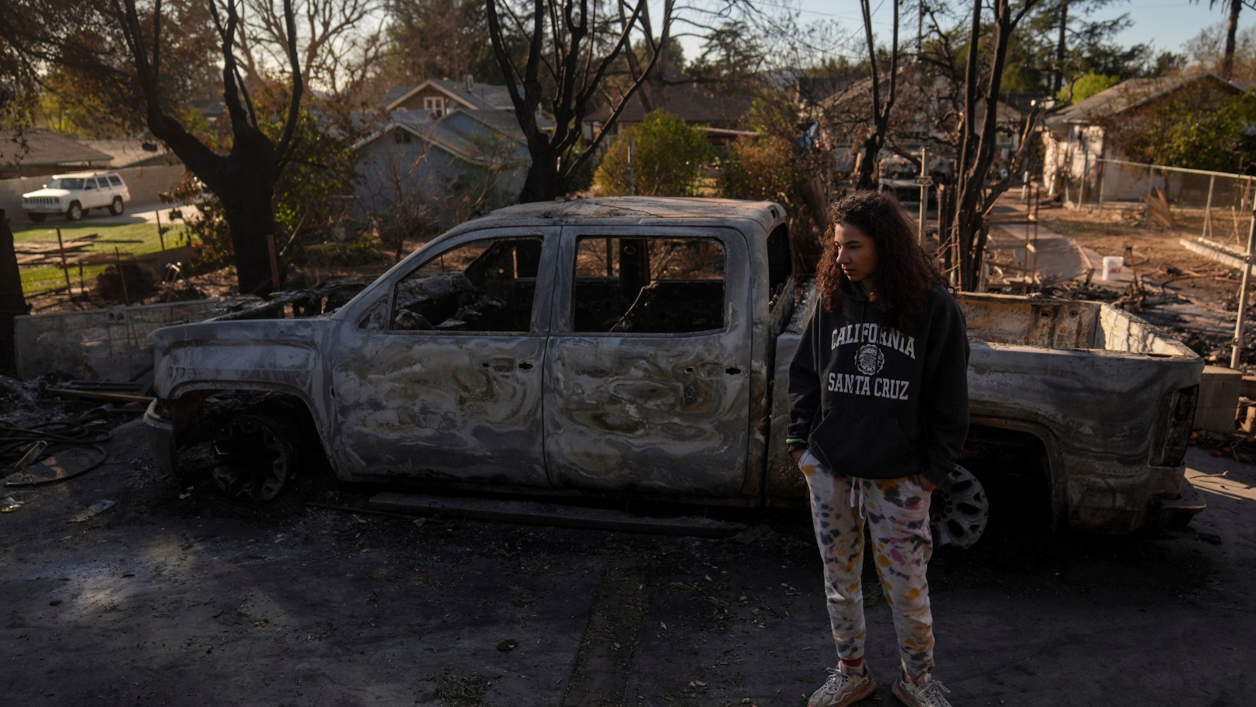 Kaylin Johnson, whose home is one of the few that survived the Eaton Fire in her neighborhood in Altadena, Calif., visits her neighbor's home Tuesday, Jan. 14, 2025. (AP Photo/Jae C. Hong)