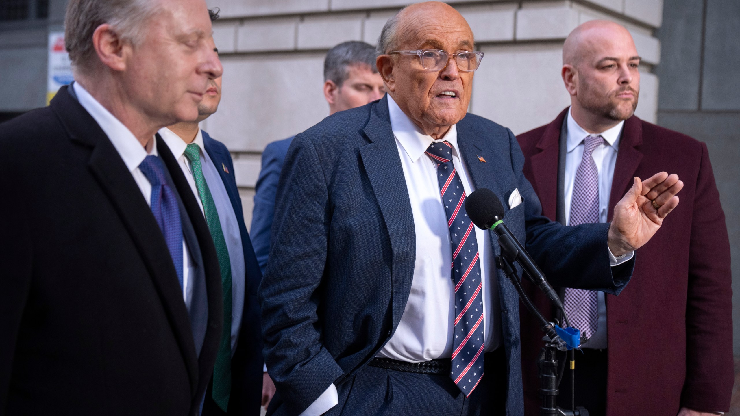 Rudy Giuliani, center, speaks to reporters after leaving federal court in Washington, Friday, Jan. 10, 2025. (AP Photo/Mark Schiefelbein)