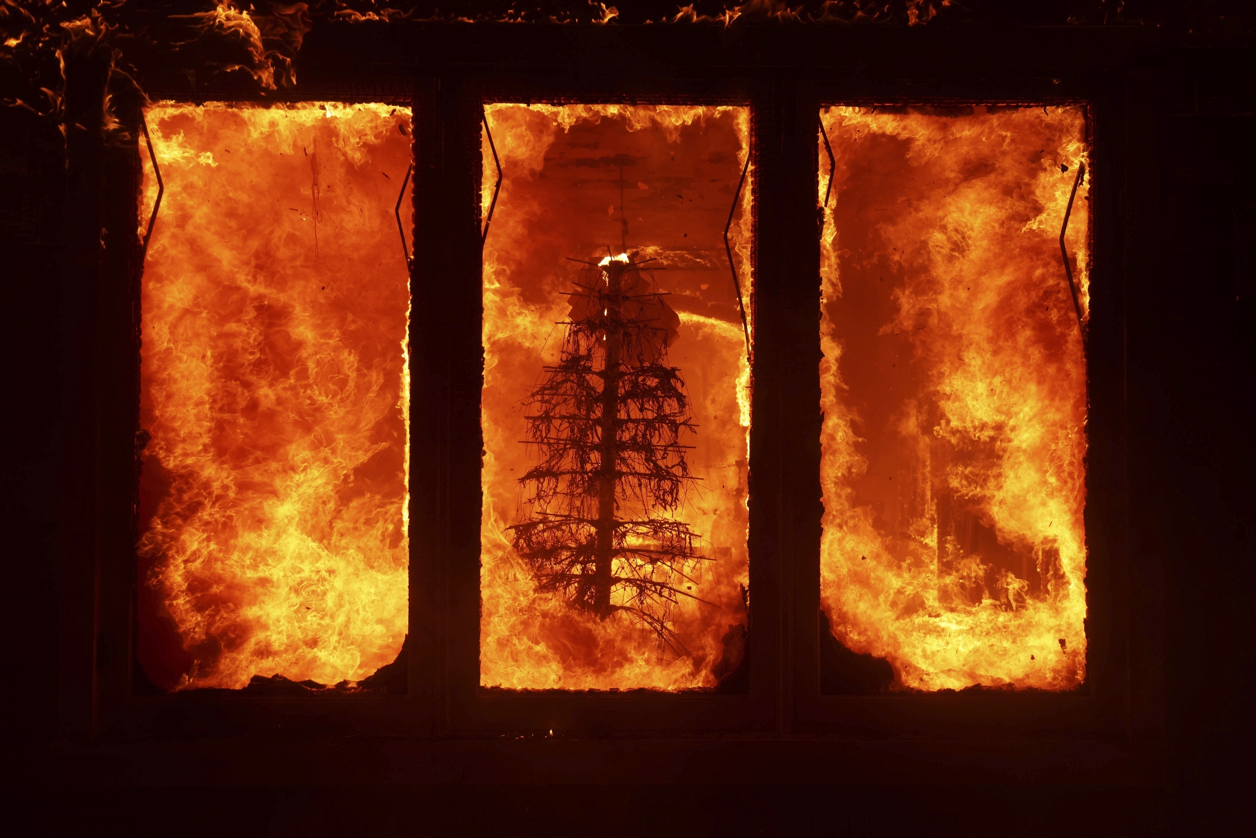 FILE - The Palisades Fire burns a Christmas tree inside a residence in the Pacific Palisades neighborhood of Los Angeles, Tuesday, Jan. 7, 2025. (AP Photo/Ethan Swope, File)