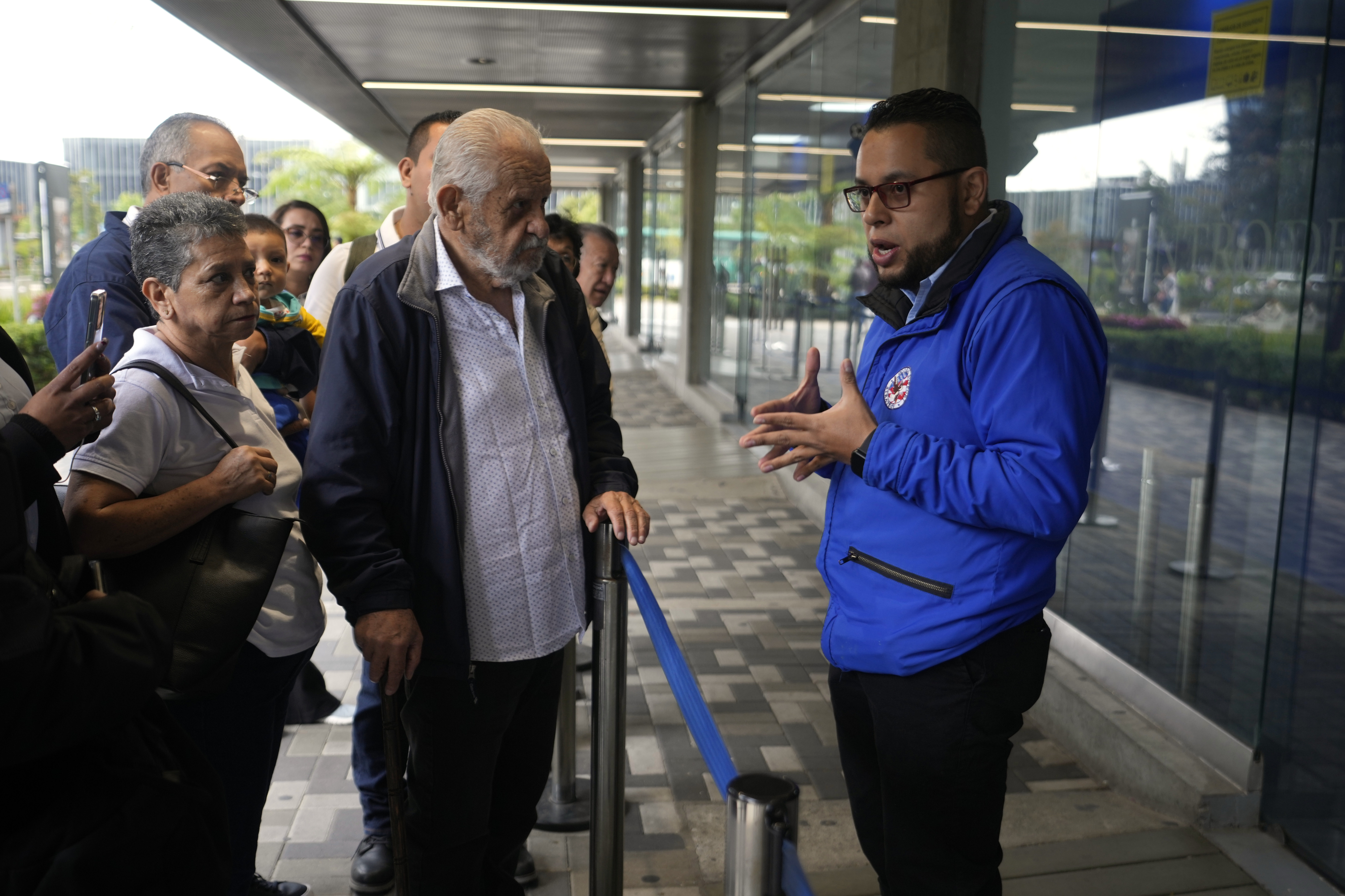 A U.S. consular official explains to people with scheduled visa document submissions that their appointments were canceled due to Colombian President Gustavo Petro's refusal to accept repatriation flights of Colombian citizens from the U.S., at a U.S. Embassy Applicant Service Center in Bogota, Colombia, Monday, Jan. 27, 2025. (AP Photo/Fernando Vergara)