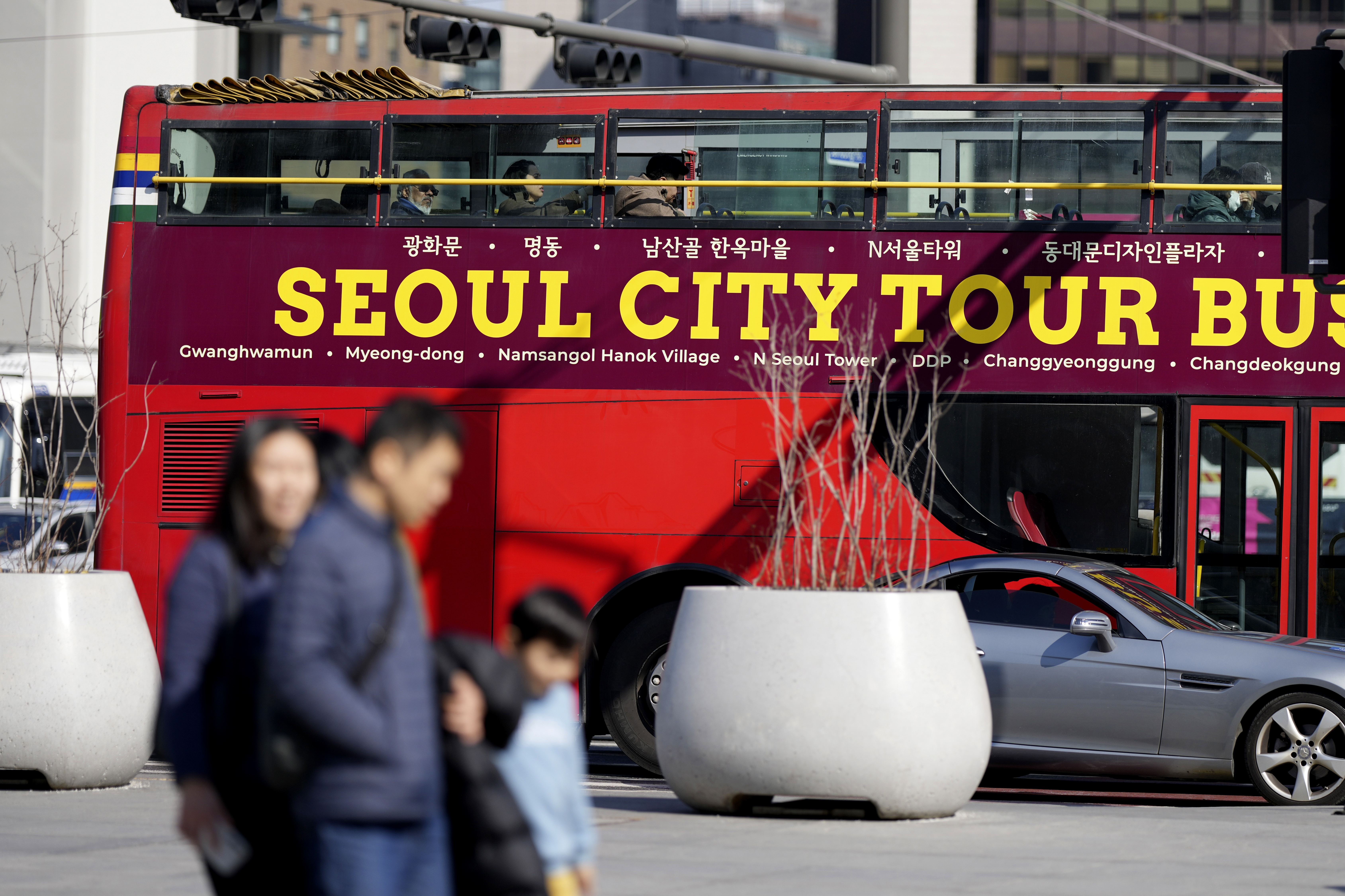 People walk near South Korea's capital Seoul tour bus in Seoul, South Korea, Thursday, Feb. 27, 2025. (AP Photo/Lee Jin-man)