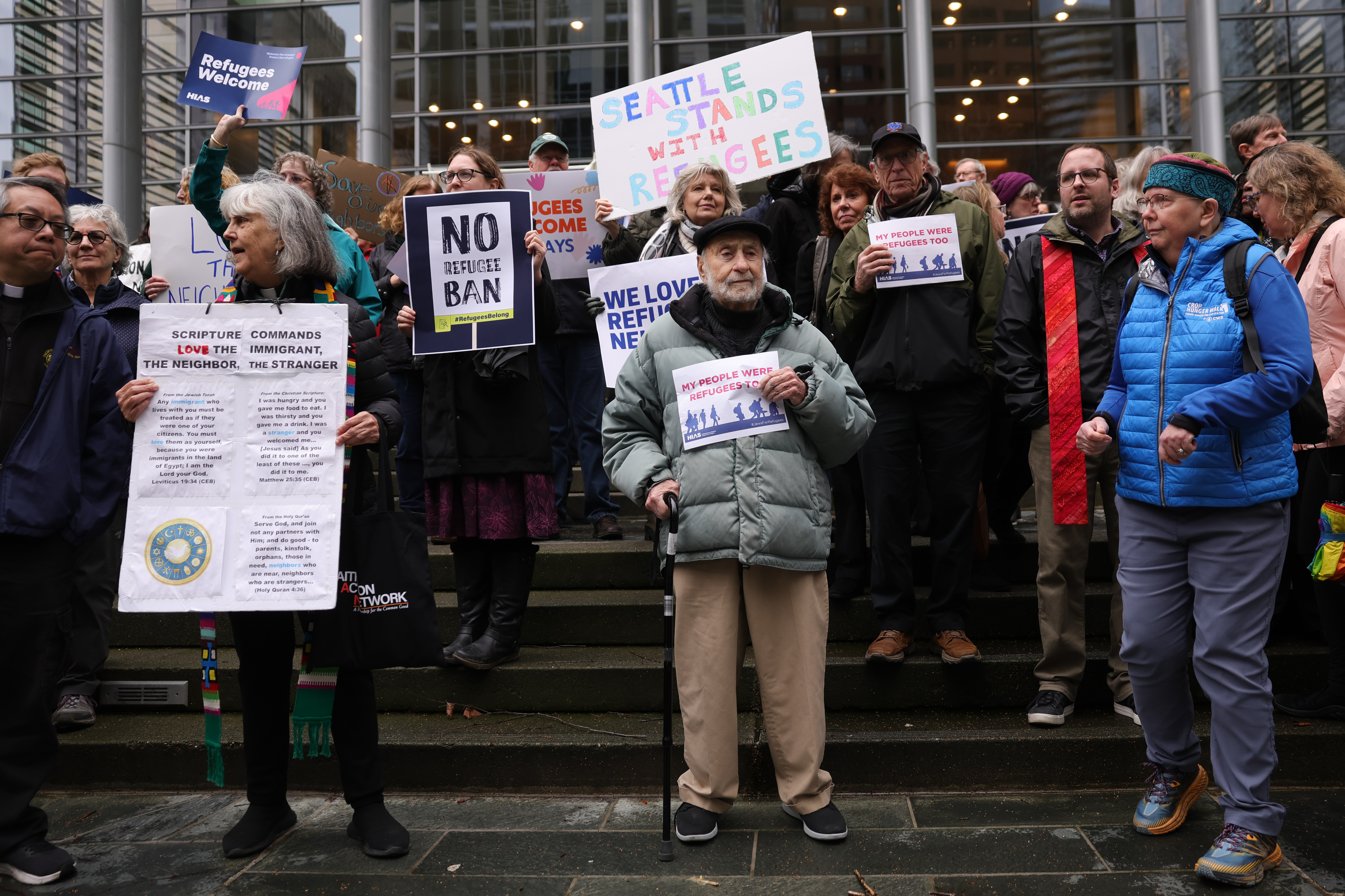 Martin Bernstein, 95, whose parents were refugees, at center, holds a sign as people gather outside the U.S. District Court after a federal judge blocked President Donald Trump's effort to halt the nation's refugee admissions system Tuesday, Feb. 25, 2025, in Seattle. (AP Photo/Ryan Sun)