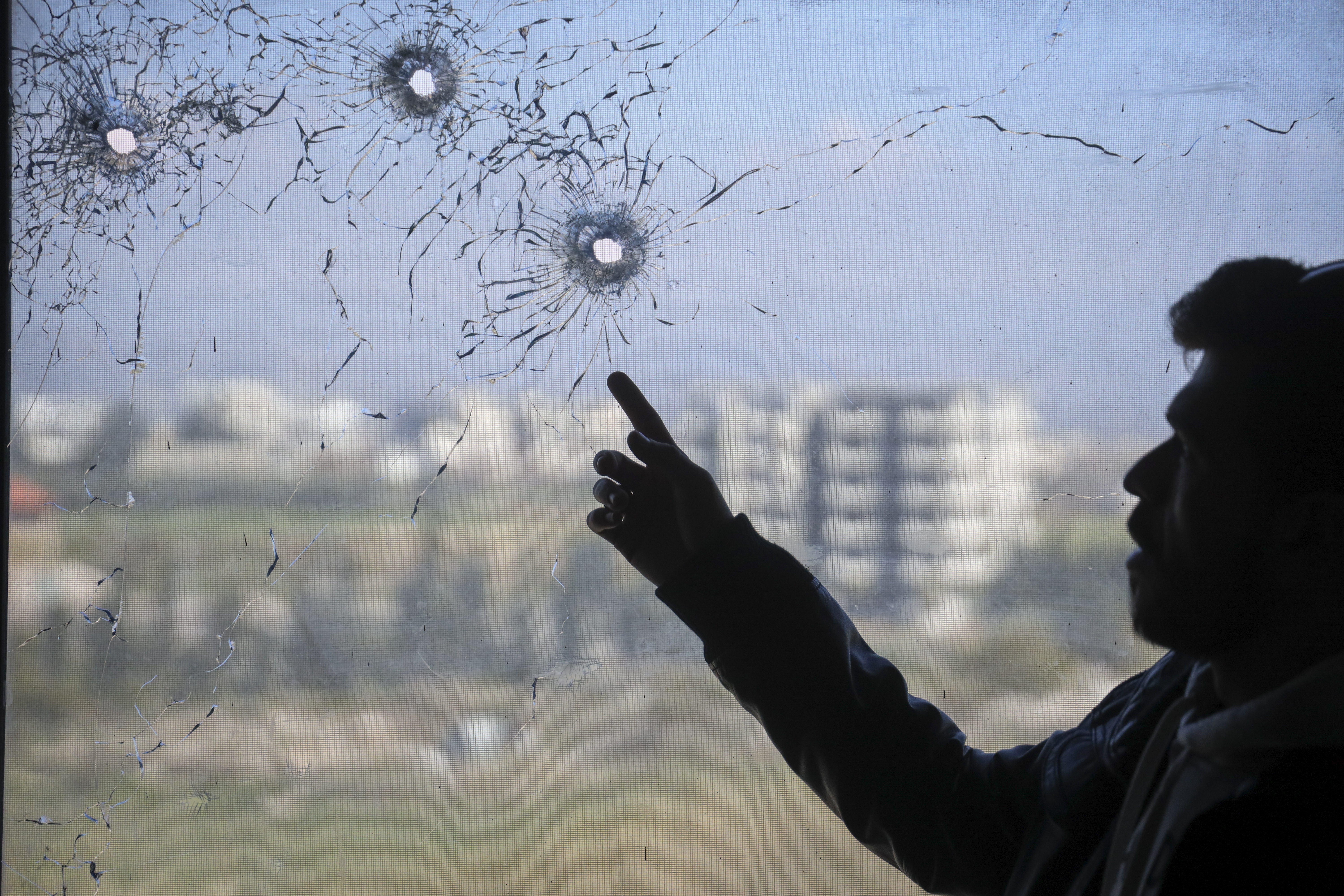 A nurse points to bullet holes in a window following the recent wave of violence between Syrian security forces and gunmen loyal to former President Bashar Assad, as well as subsequent sectarian attacks, at a hospital in the town of Jableh, in Syria's coastal region, on Monday, March 10, 2025. (AP Photo/Omar Albam)